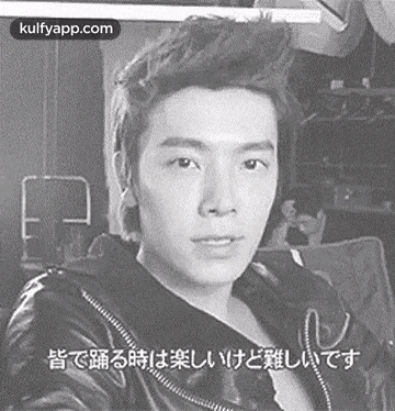 a black and white photo of a young man in a leather jacket with chinese writing on it .