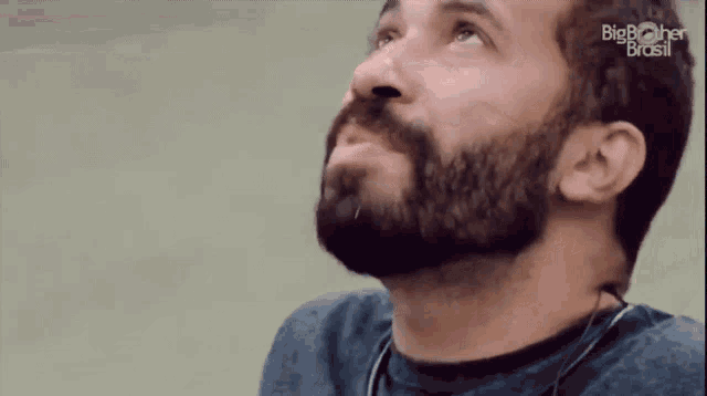 a man with a beard is wearing headphones and looking up at the sky .