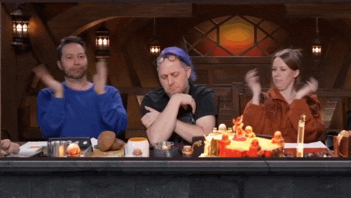 a group of people are sitting at a table with a cake on it