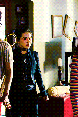 a woman in a black jacket stands in a living room
