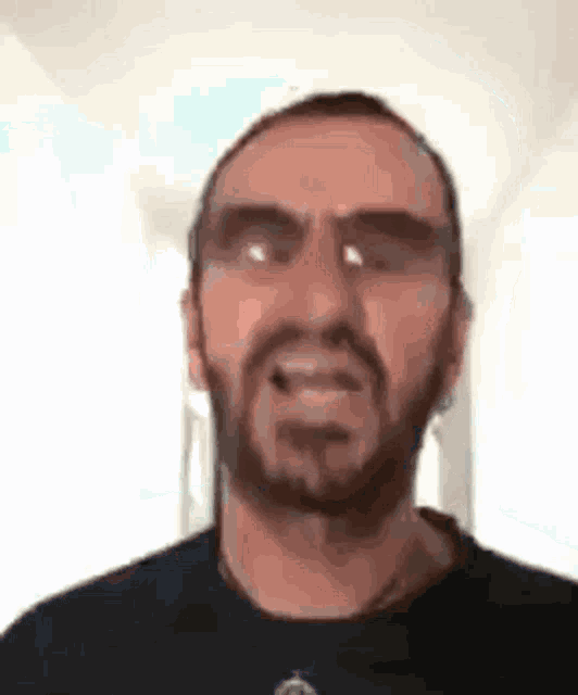 a man with a beard is making a funny face while wearing sunglasses and a black shirt .