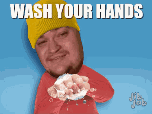 a man wearing a yellow hat is washing his hands with soap