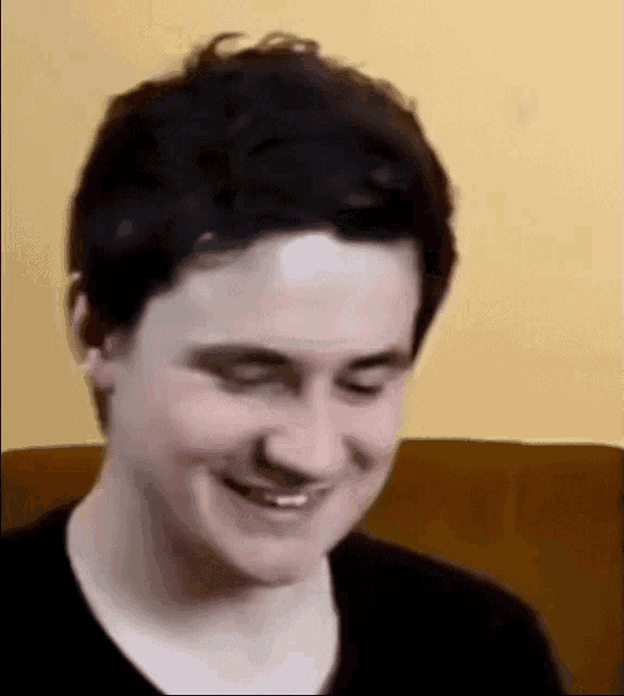 a young man is sitting on a couch and smiling .