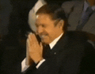 a man in a suit and tie with his hands folded in prayer