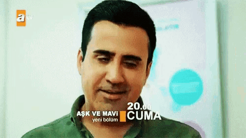 a man in a green shirt is smiling in front of a sign that says cuma
