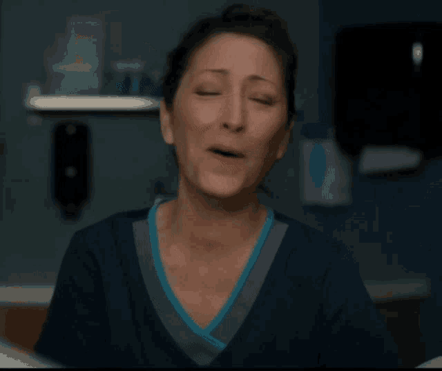 a woman in a blue scrub top is crying with tears running down her face