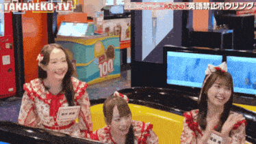 three girls are sitting in a bowling alley in front of a sign that says 100