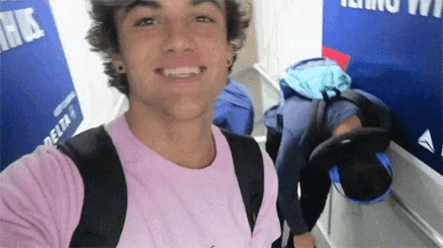 a man in a pink shirt is taking a selfie in front of a sign that says delta