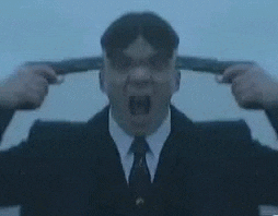 a man in a suit and tie is holding a gun to his ear .