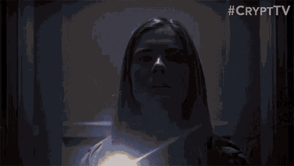 a woman is standing in front of a door with a glowing light coming out of her chest .