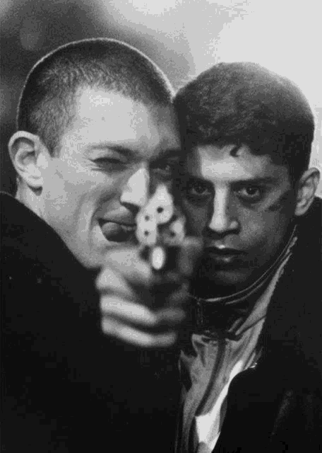 a black and white photo of two men pointing guns