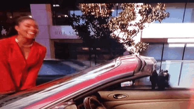 a woman in a red suit is standing in front of a pink car with the word hotel on it