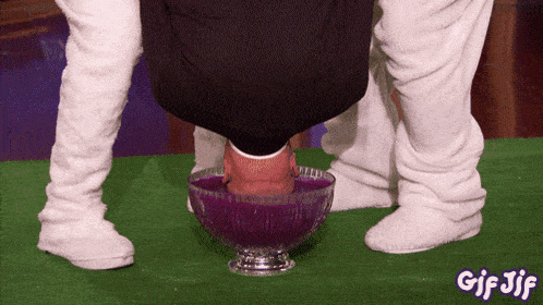 a man 's head is in a bowl of purple liquid with gif jif written on the bottom right