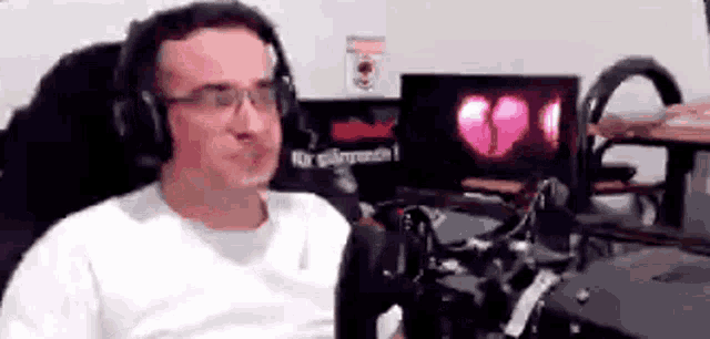 a man is wearing headphones and glasses while sitting in front of a microphone .