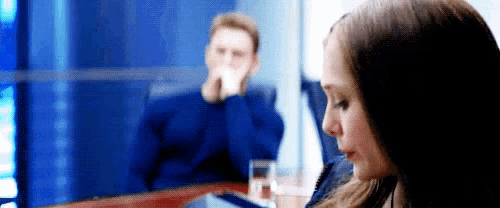 a man and a woman are sitting at a table drinking water .