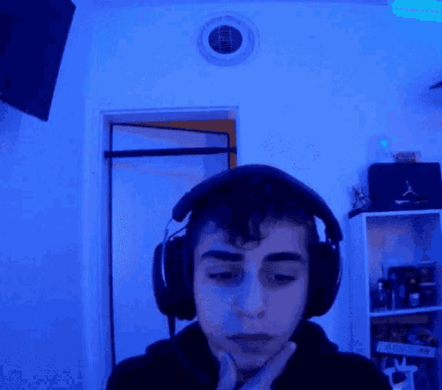 a young man wearing headphones is sitting in a room with blue lights .