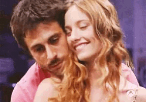 a man and a woman are hugging and smiling . the woman is wearing a pink shirt .