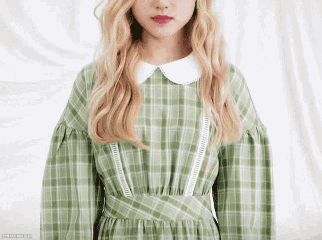 a woman wearing a green plaid dress with a white collar and red lipstick