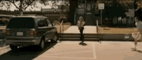 a van is parked in a parking lot in front of a school while a person skateboards .