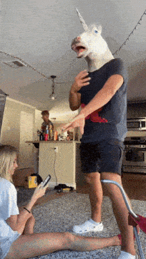a man wearing a unicorn mask is talking to a woman