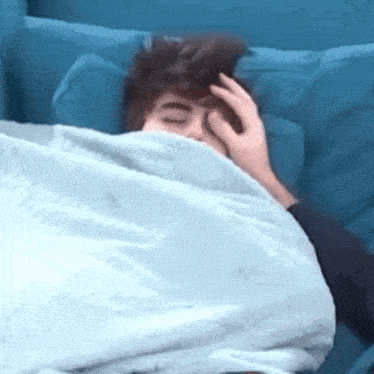 a person laying in a bed with a blue blanket
