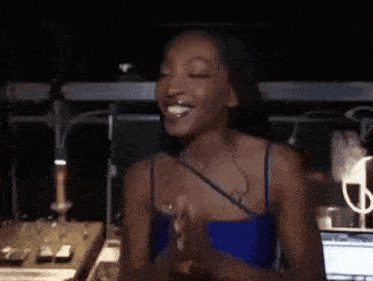 a woman in a blue tank top is smiling and clapping