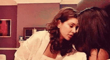 two women are kissing each other on the forehead in a room .