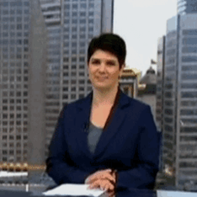 a woman in a suit is sitting at a desk in front of a city skyline