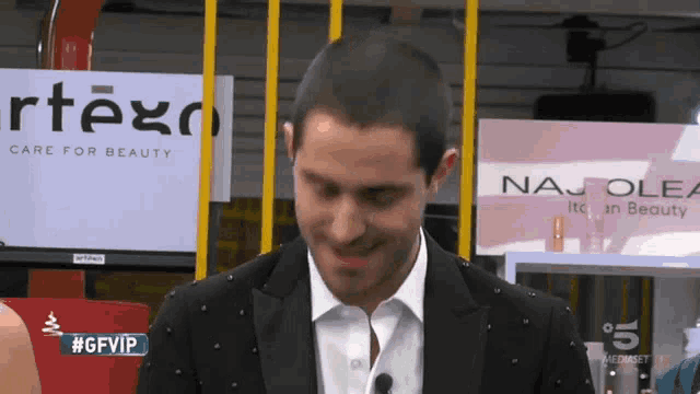 a man in a suit is standing in front of a sign that says care for beauty