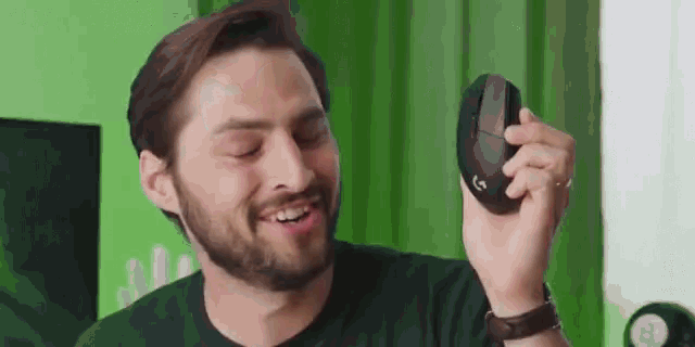a man with a beard is smiling while holding a computer mouse