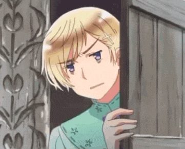 a boy with blonde hair and blue eyes is peeking out from behind a wooden door