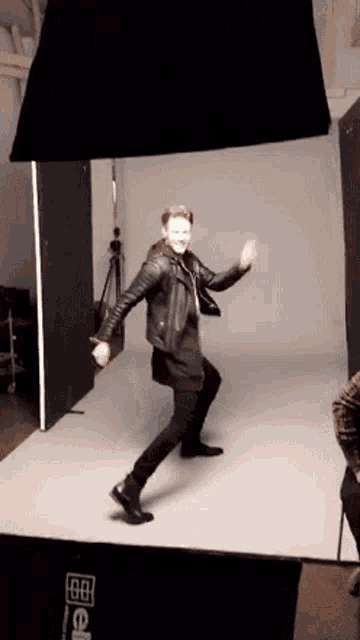 a man in a leather jacket is dancing in front of a sign that says ' 88 ' on it