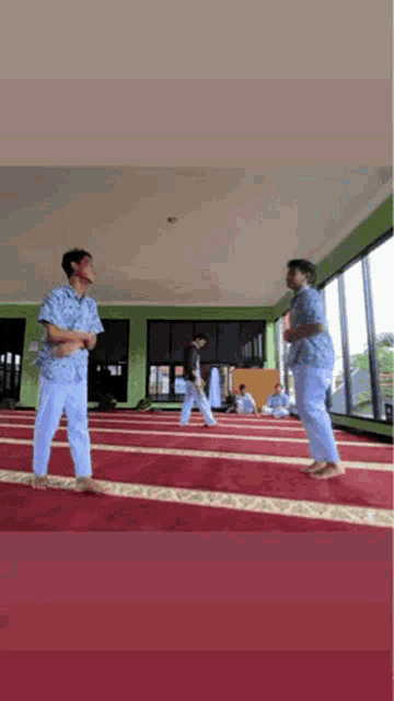 two men are standing on a carpet in a mosque