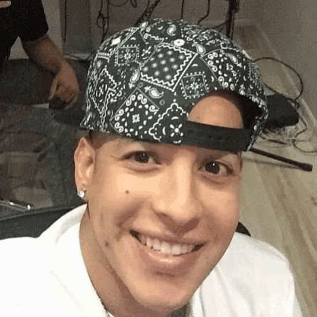 a man wearing a bandana and a baseball cap is smiling for the camera .