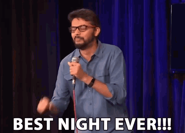 a man is holding a microphone in front of a blue curtain and says " best night ever "