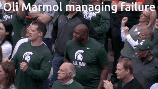 a man wearing a green shirt that says all day stands in a crowd