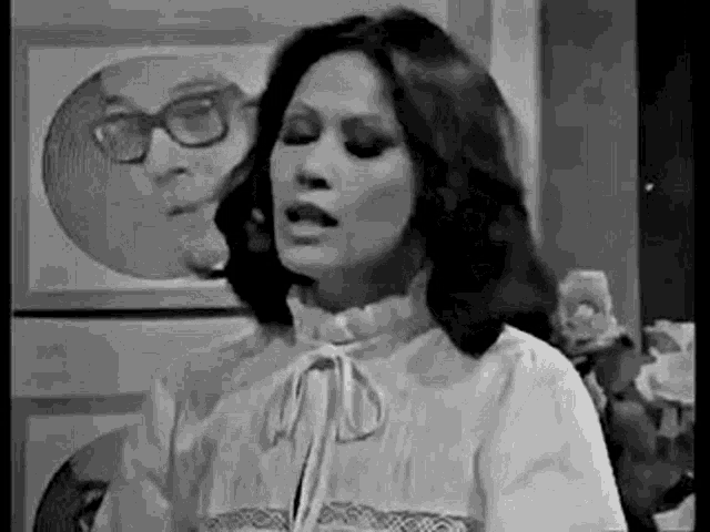 a black and white photo of a woman wearing glasses making a funny face .