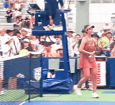 a woman walking on a tennis court in front of a wilson advertisement