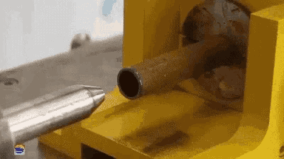 a machine is cutting a metal pipe with a sharp tool .