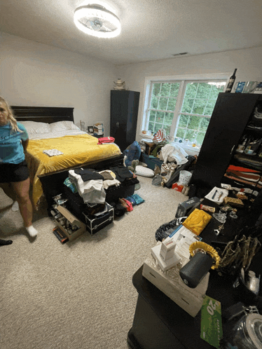 a woman in a blue shirt that says ' i love you ' on it stands in a messy room