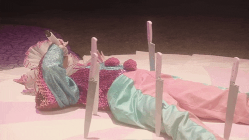 a clown is laying on the ground with knives sticking out of her clothes