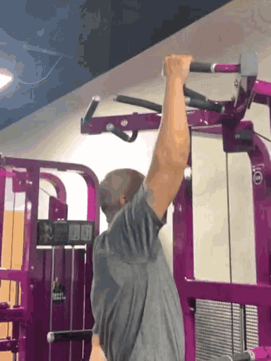 a man in a gray shirt is using a machine that says planet fitness