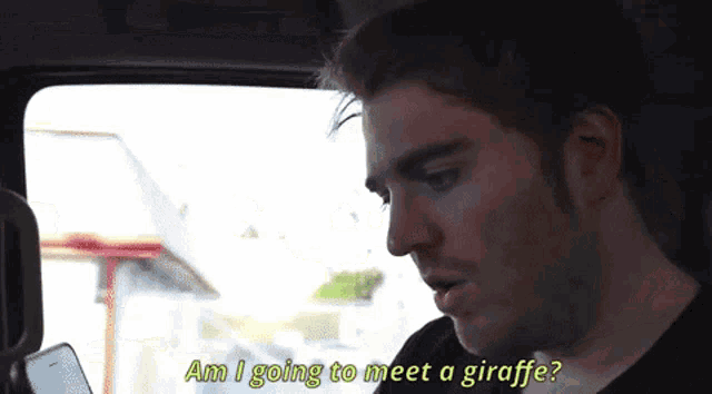 a man in a car is talking to another man and says am i going to meet a giraffe