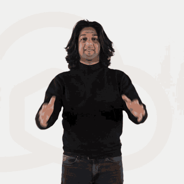 a man with long hair wearing a black sweater and jeans