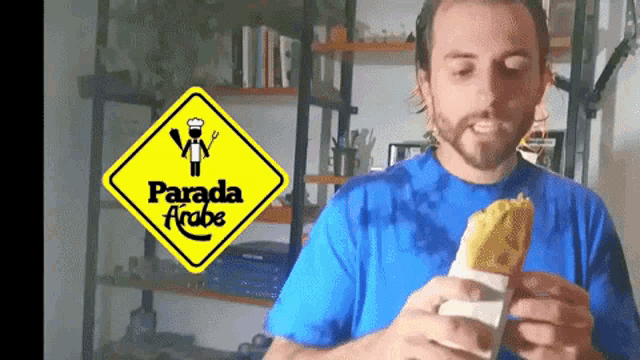 a man eating a sandwich in front of a yellow sign that says parada arbe