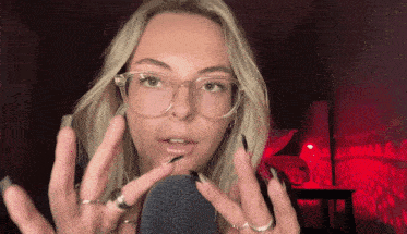 a woman wearing glasses and rings holds her hands to her face