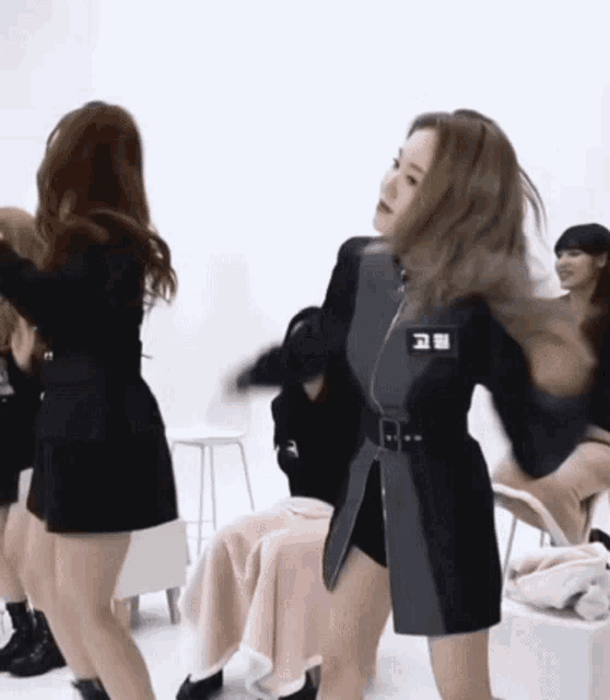 a group of women are dancing in a room while sitting on chairs .