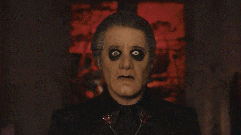 a man in a black suit with black eyes and a bow tie