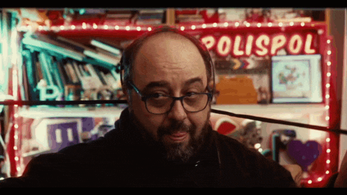 a man wearing glasses stands in front of a red sign that says polispol