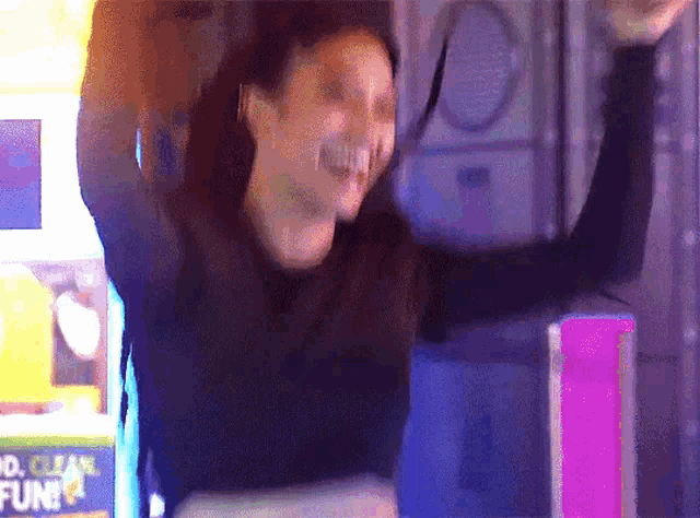 a woman holds her arms in the air in front of a sign that says ' clean fun '